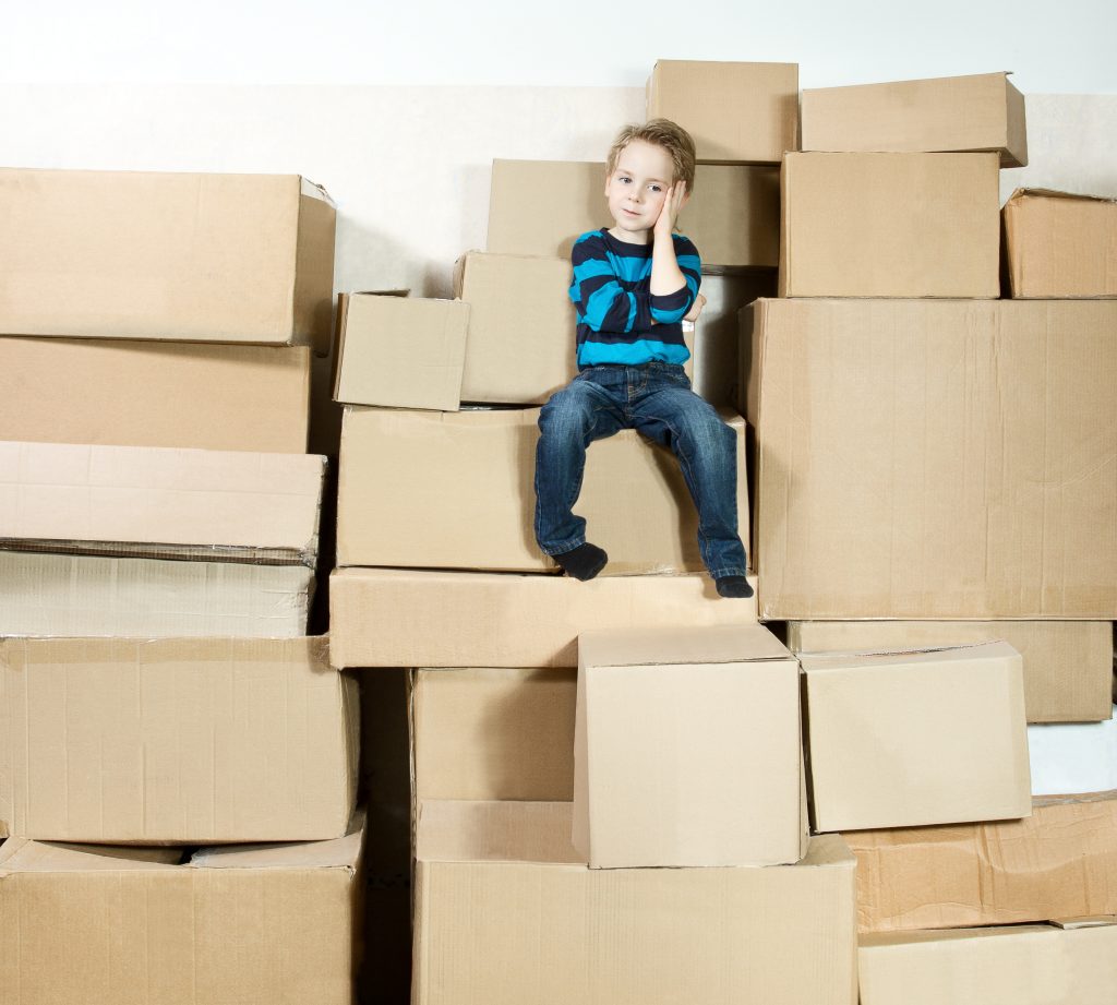 Das Bild zeigt einen Jungen, der mit Paketen umgeben ist und nicht weiß, was er mit diesen tun sollte